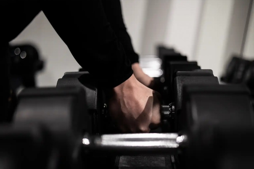 Een sporter pakt een dumbbell uit het rek bij Vital-GO.