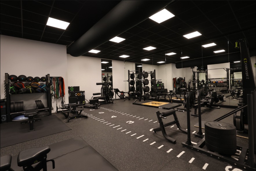 Breed overzicht van de functionele trainingszone met sprintbaan, racks en vrije trainingsruimte.