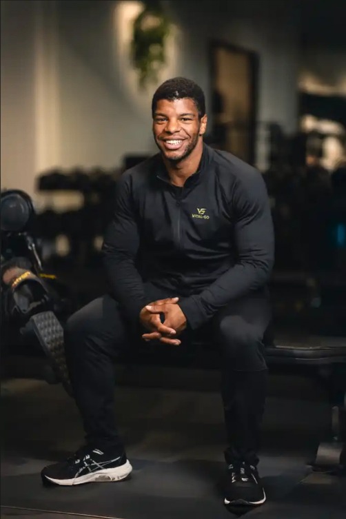 Luciano, personal trainer bij Vital-GO, zittend op een halterbank.
